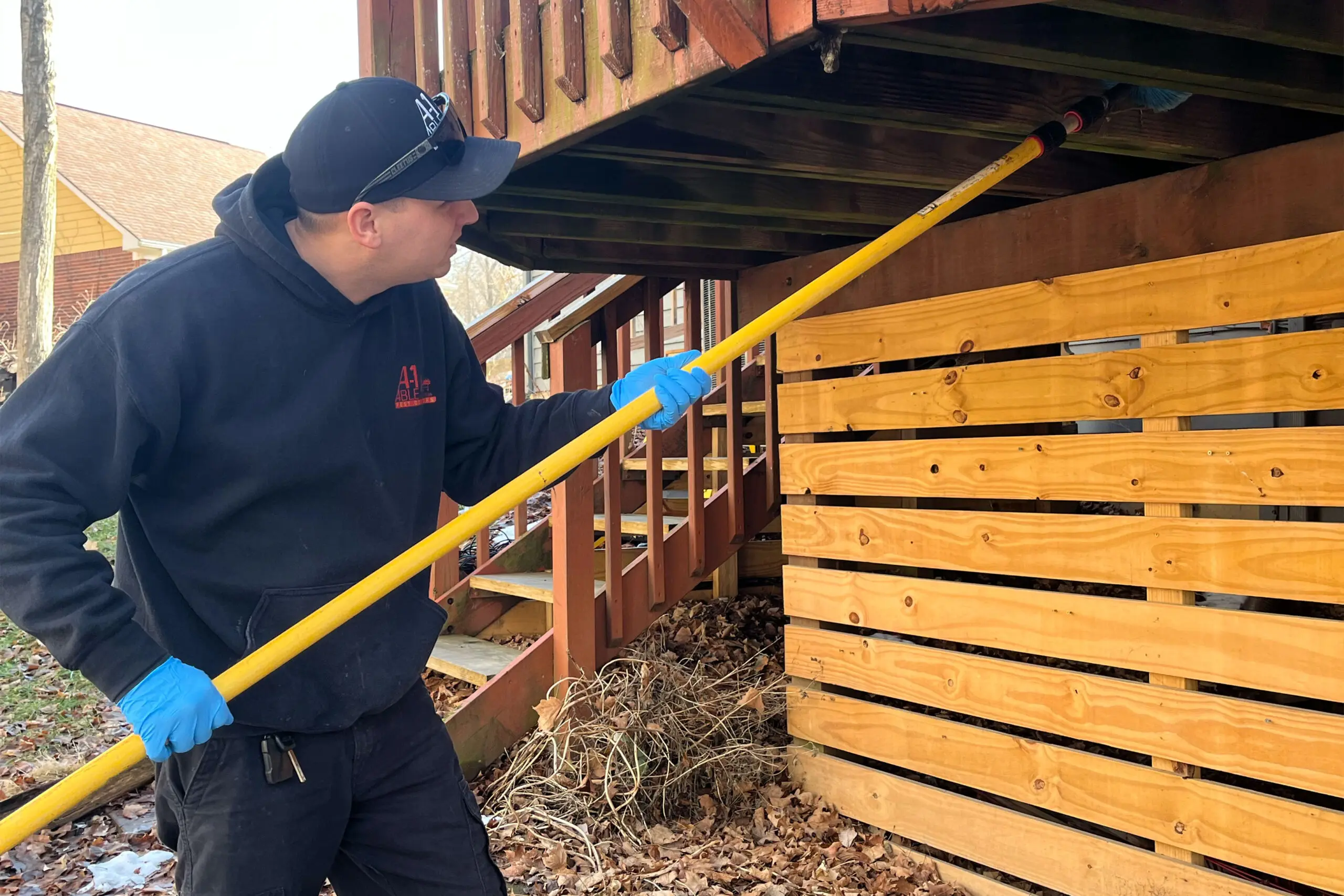 A-1 Able Pest Doctors technician inspecting under a deck for spider webs.